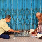 Two elderly men enjoy a strategic game of chess on the streets of Jambi, Indonesia.