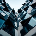 A low-angle view of futuristic modern architecture featuring unique geometric patterns and glass facade.