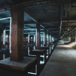 Explore the eerie ambiance of an abandoned industrial structure illuminated by neon lights and water reflections.