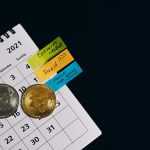 Close-up of Bitcoins on a calendar highlighting investment plans with sticky notes.