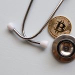 A stethoscope with a Bitcoin coin symbolizing the intersection of healthcare and cryptocurrency.