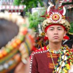Man in vibrant traditional attire participates in cultural festival parade.