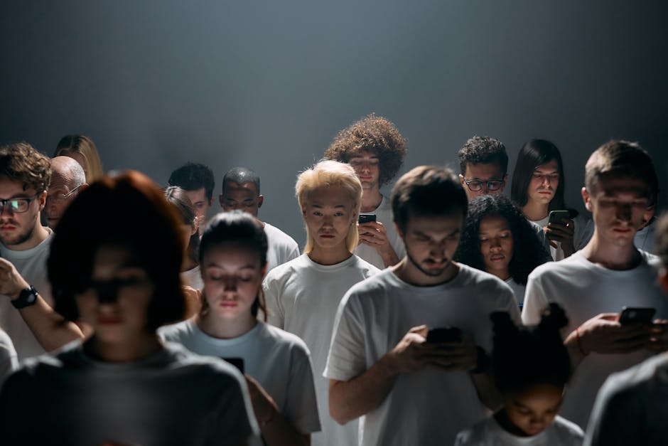 A diverse crowd focused on smartphones, illustrating social isolation and technology connection.