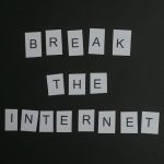 Conceptual flat lay of 'Break the Internet' message with white letters on a black background.
