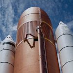 Dramatic view of rocket boosters against a bright blue sky, showcasing aerospace technology.