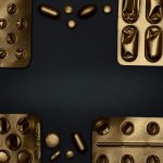 Close-up of metallic pills and blister packs on a dark surface, showcasing healthcare themes.
