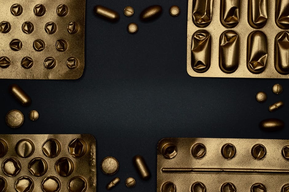 Close-up of metallic pills and blister packs on a dark surface, showcasing healthcare themes.
