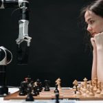 Woman strategizing a chess game against a robot arm, illustrating technology and strategy.