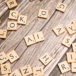Wooden letter tiles scattered on a textured surface, spelling 'AI'.