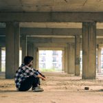 Young man sitting thoughtfully in an urban under-construction building in Noida, India.