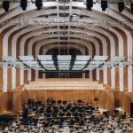 Spacious modern auditorium featuring wooden interior architecture and empty seating.