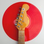 Creative close-up of an electric guitar headstock with a red vinyl record. Perfect for music-themed designs.