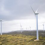 Majestic wind turbines harnessing energy in a vast green landscape under cloudy skies.