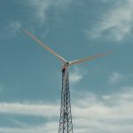 A towering wind turbine stands tall, harnessing wind energy under a clear blue sky.