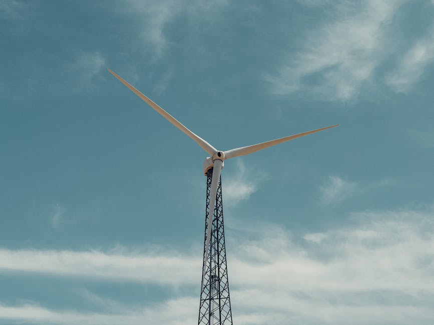 A towering wind turbine stands tall, harnessing wind energy under a clear blue sky.