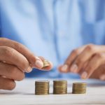 Close-up of hands stacking gold coins, symbolizing financial growth and savings.