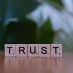 Wooden letter tiles spelling TRUST on a wooden surface, symbolizing integrity and values.