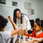 Engaging classroom scene with teacher guiding children in a chess game, fostering learning and fun.