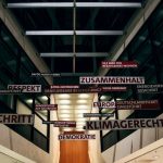 An architectural interior in Berlin featuring suspended German words and phrases highlighting social themes.
