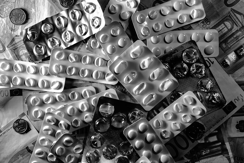 Black and white image of pill blister packs scattered on euro bills and coins.