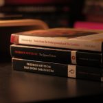 Stack of classic books by Dostoevsky and Nietzsche on a dark desk.