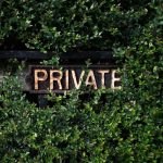 A rustic 'Private' sign nestled within lush green foliage, suggesting seclusion.