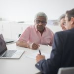Senior couple discussing insurance options with a consultant in an office setting.