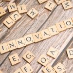 Creative display of 'Innovation' spelled with wooden letter tiles on a wooden surface.