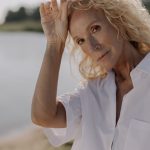Portrait of a senior woman with blonde hair posing outdoors in sunlight.