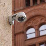 Wall-mounted dome security camera on a city building, enhancing public safety.