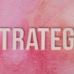 Wooden letters spelling 'Strategy' on a pink textured background.