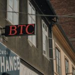 Exterior of a building featuring a prominent BTC and exchange sign, indicating a cryptocurrency location.