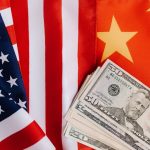 From above of United States banknotes placed on national flags of America and China illustrating international trade concept