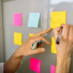 Focused businessman writing ideas on sticky notes for planning and organization.