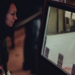 A woman peers into a store display case, considering her shopping options.