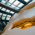 A stunning modern architectural ceiling with a curved skylight and unique lighting elements.