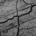 Black and white of abstract background of rough dry cracked ground in daytime