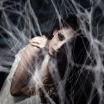 Mysterious woman trapped in spiderwebs creating a Halloween-themed eerie atmosphere.