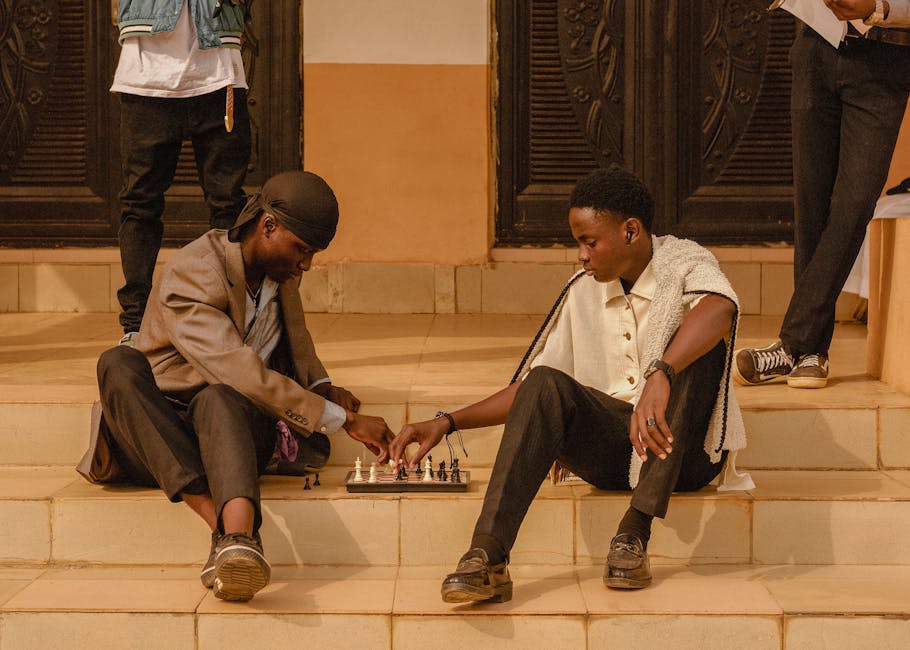 Two young men playing chess on steps outdoors in Ado Ekiti, Nigeria.