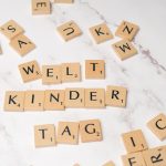 Scrabble tiles forming the words 'Welt Kinder Tag' on a marble background, symbolizing children's day.