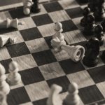 A monochrome vintage-style shot of a chess game in progress with scattered pieces.