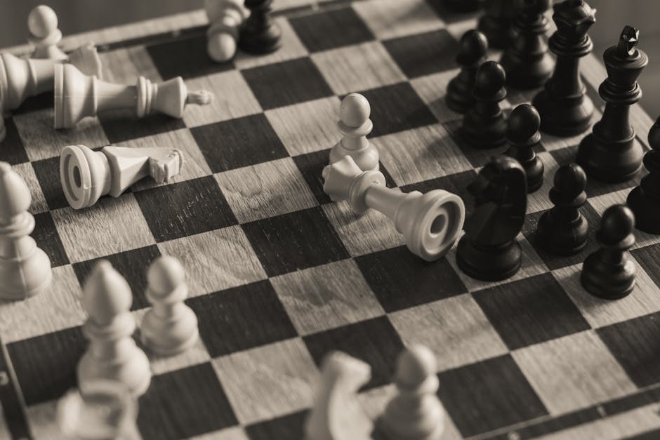 A monochrome vintage-style shot of a chess game in progress with scattered pieces.