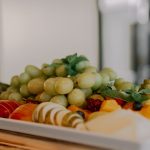 A vibrant assortment of fruits including grapes, apples, and berries on a white tray.