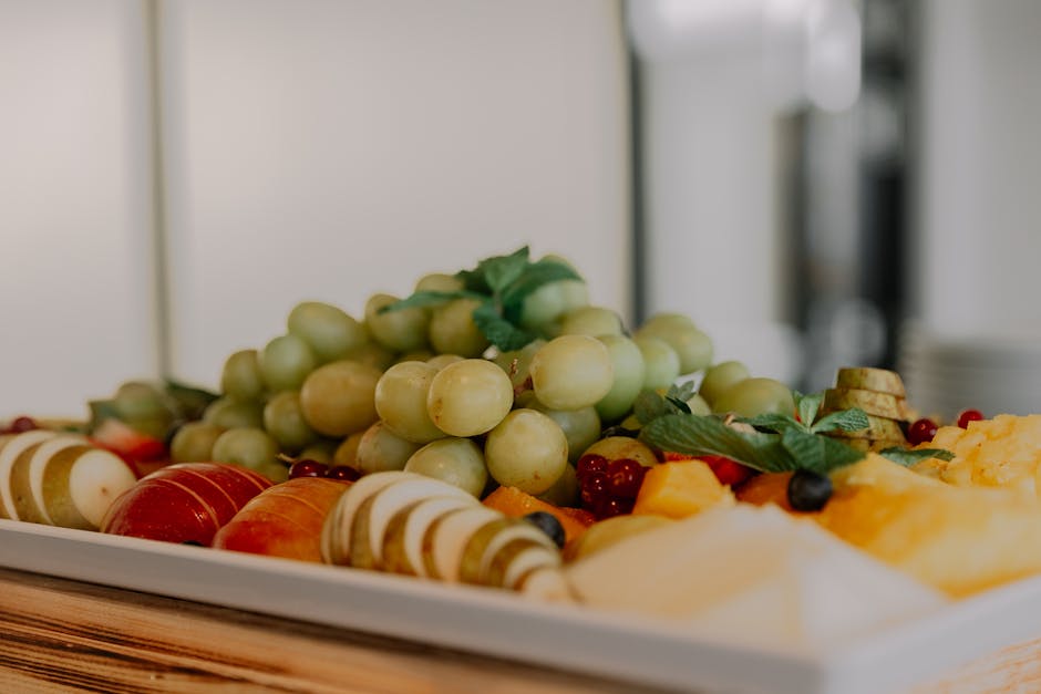 A vibrant assortment of fruits including grapes, apples, and berries on a white tray.