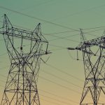 Silhouette of high voltage power lines against a twilight sky, illustrating energy infrastructure.