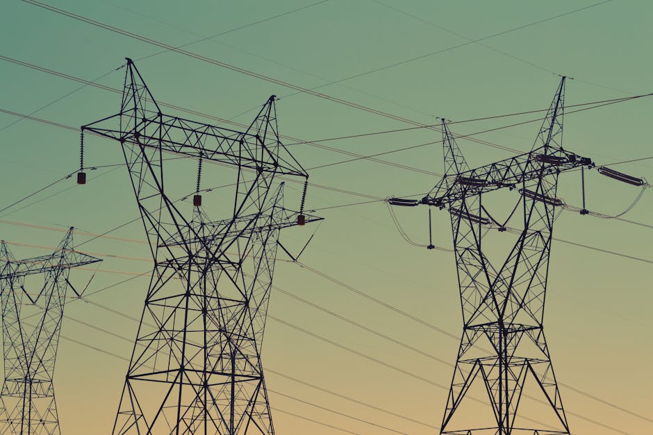 Silhouette of high voltage power lines against a twilight sky, illustrating energy infrastructure.
