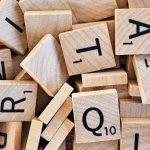 Pile of wooden Scrabble tiles showcasing various letters and numbers.