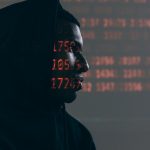 Side profile of a man in a hoodie, surrounded by red code, depicting cybersecurity theme.