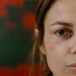 Close-up portrait of a woman with a bruised eye, depicting emotion and resilience.