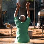 A senior man raises his arms during a sunny day outdoors in Manila.